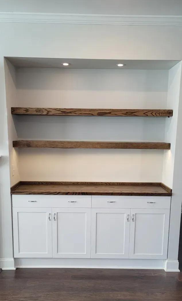 Built-in white cabinet with two rustic wood shelves and recessed spotlights in a wall niche