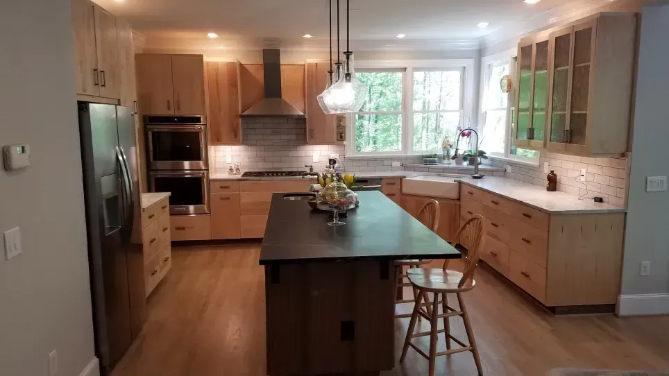 Modern kitchen with large island, wood cabinets, stainless appliances, and bright window light