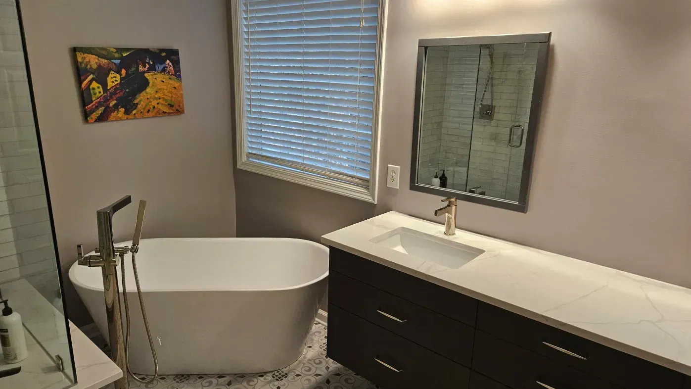 Modern bathroom with a freestanding tub, long vanity, mirror, and window blinds
