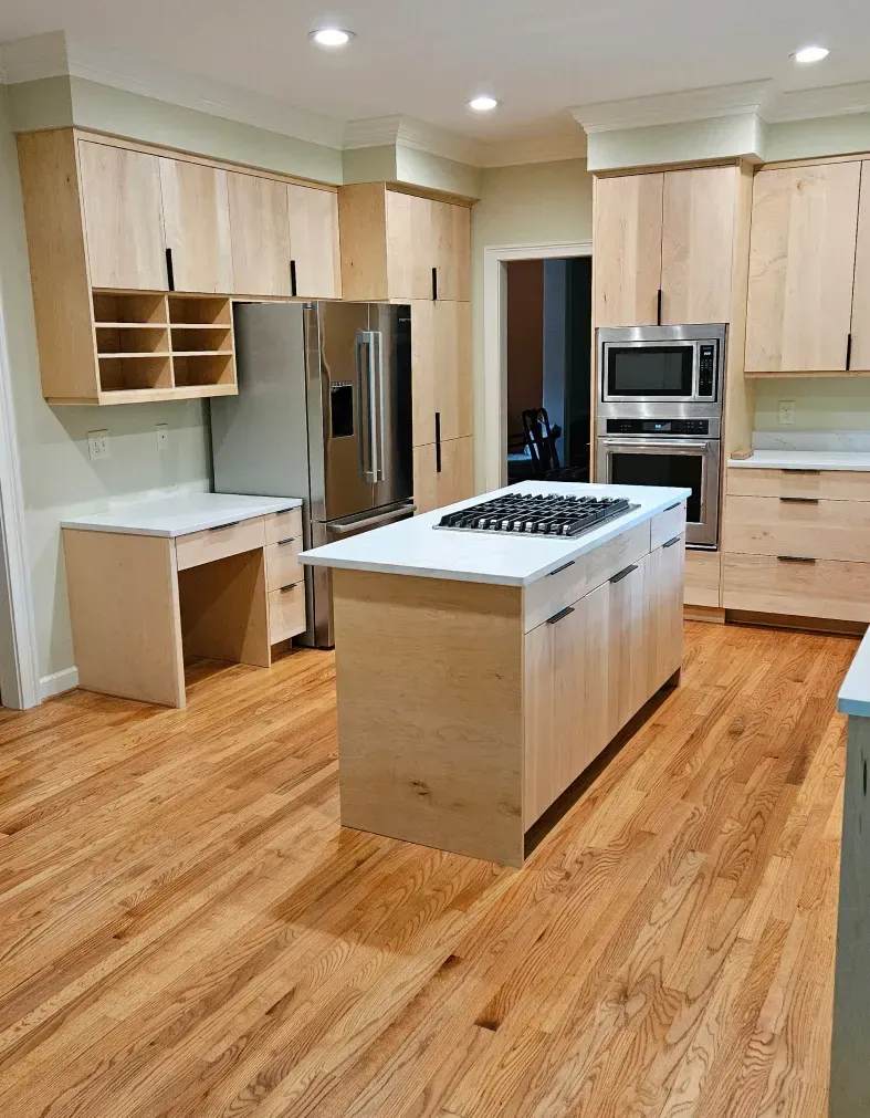 Modern kitchen with light wood cabinets, stainless steel appliances, and a central island on hardwood floors