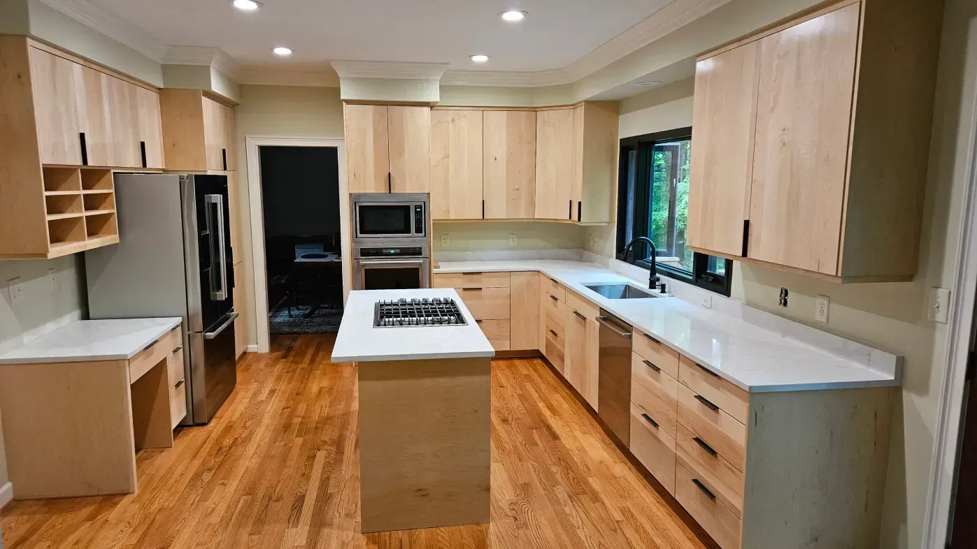 Bright kitchen with light wood cabinets, white countertops, island stove, and hardwood floors