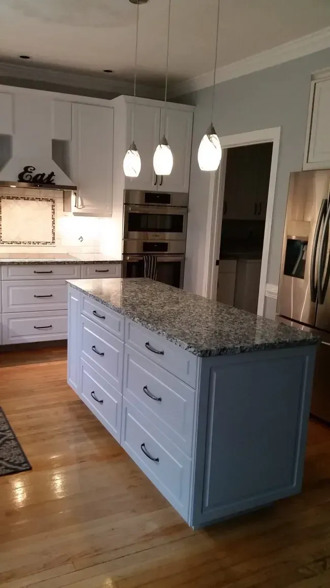 Modern kitchen with white cabinets, granite island, and hanging pendant lights