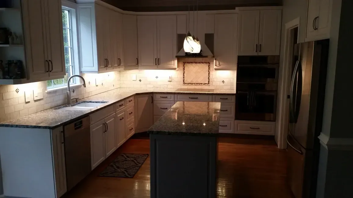 Bright white kitchen with an island, dark wood floors, and built-in appliances.