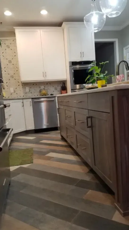 Modern kitchen with white cabinets, gray island, stainless dishwasher, and patterned runner rug.