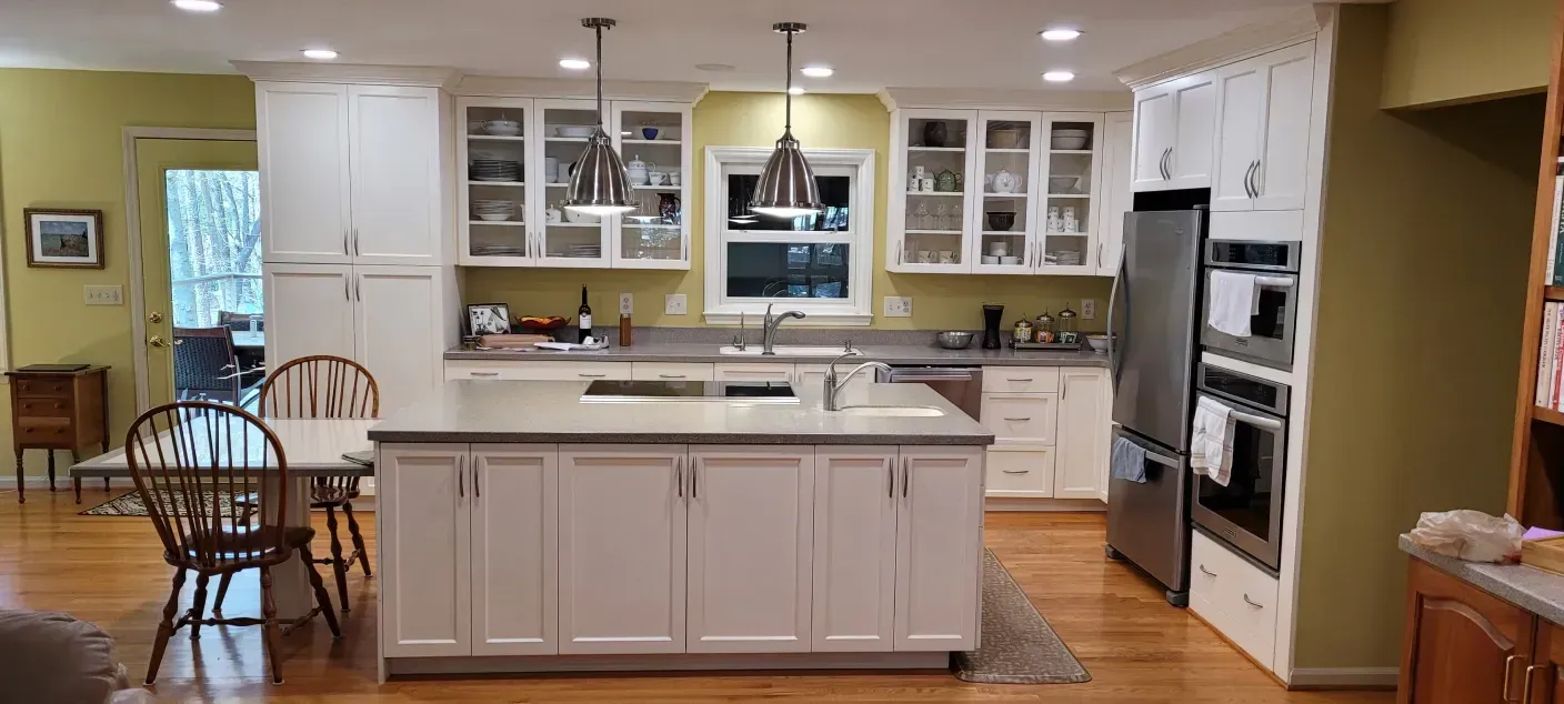 Bright kitchen with white cabinets, central island, hardwood floors, and stainless steel appliances