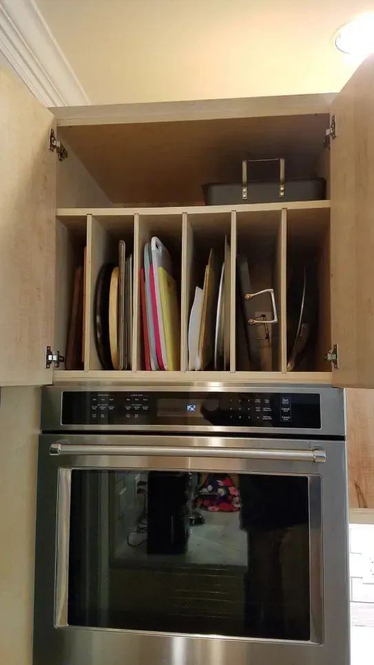 Kitchen cabinet with dishes stored above a built-in stainless steel oven