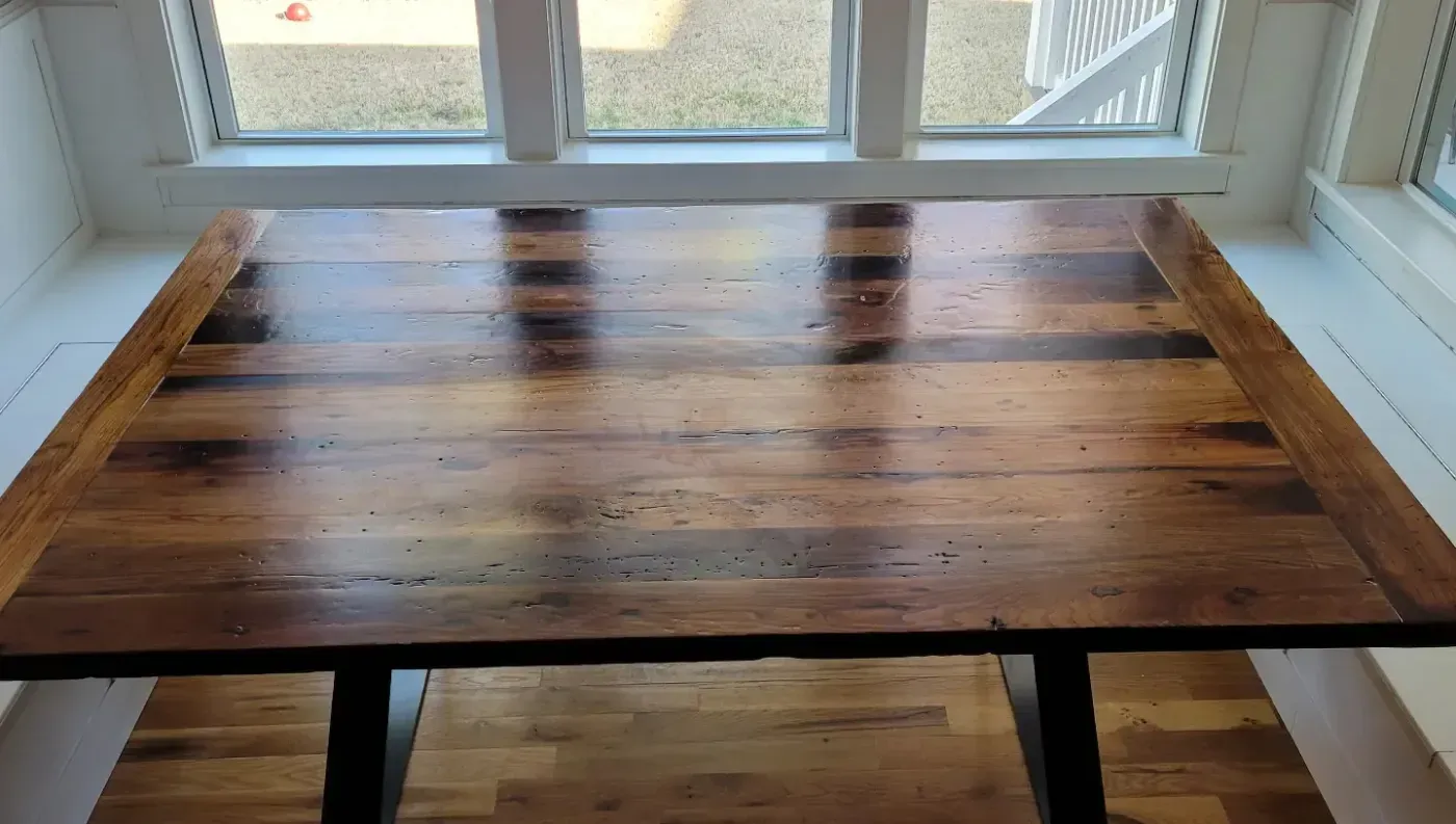 Wooden table by a bright window with sunlight reflecting on the polished surface