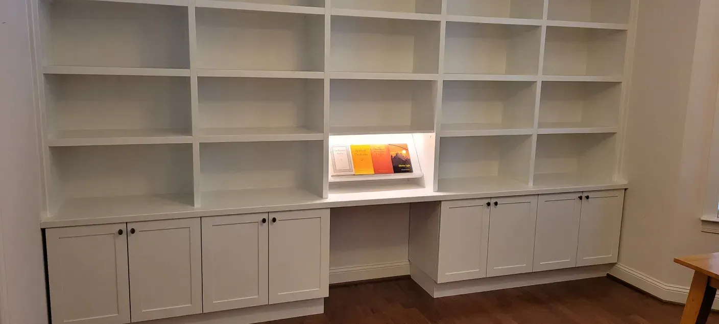 Built-in white shelving wall with cabinets and a small lit display in the center.