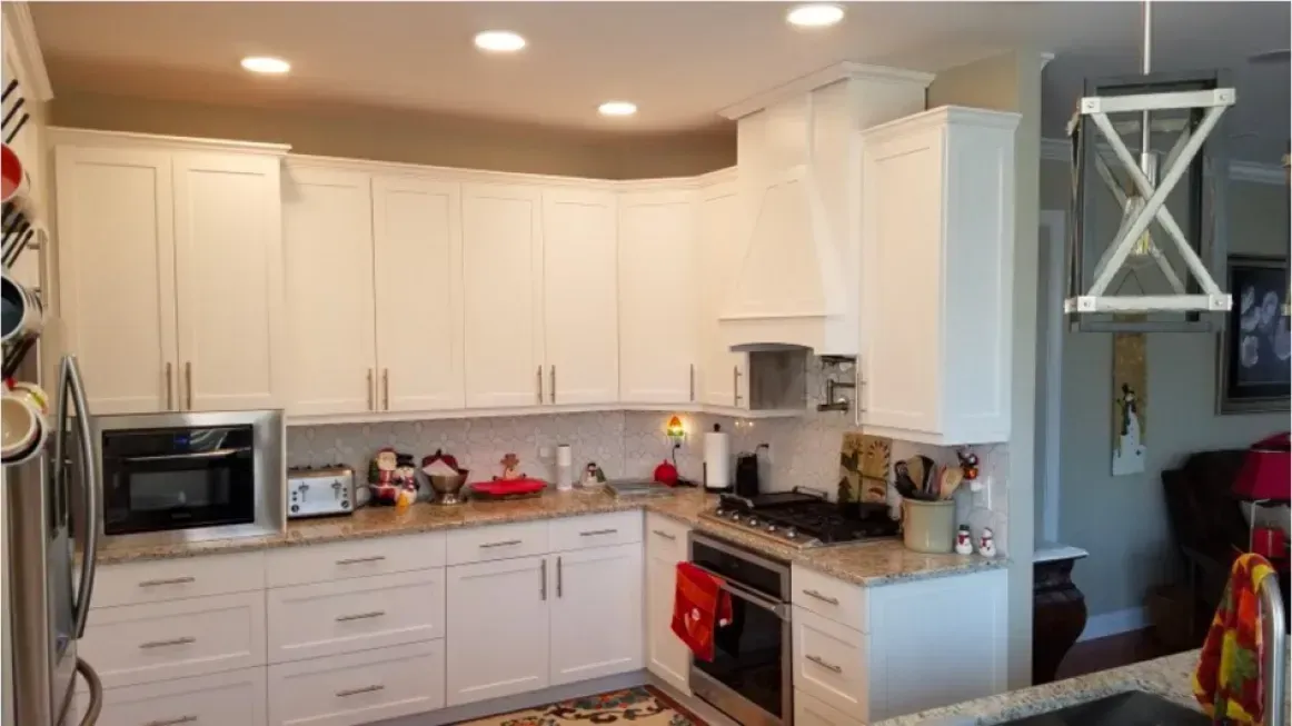 Bright white kitchen with cabinets, granite counters, stainless appliances, and ceiling lights