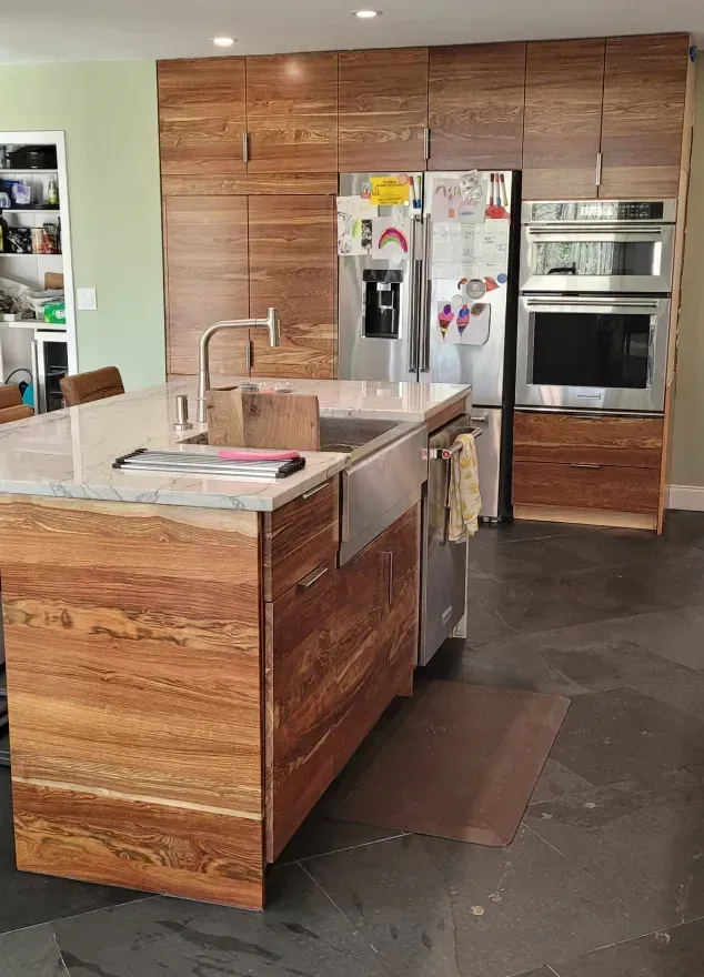 Modern kitchen with wood cabinets, island sink, stainless appliances, and gray tile floor