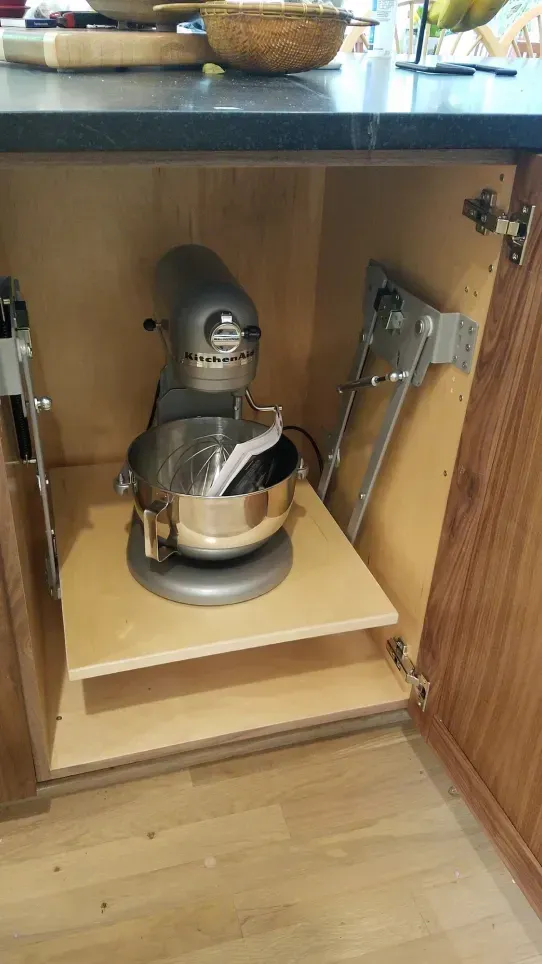 Stand mixer on a pull-out shelf inside a kitchen cabinet