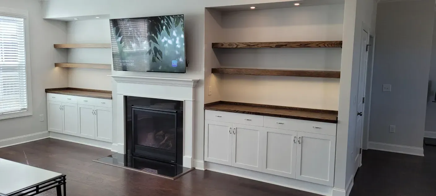 Living room wall with a fireplace, built-in shelves, and white cabinets on either side