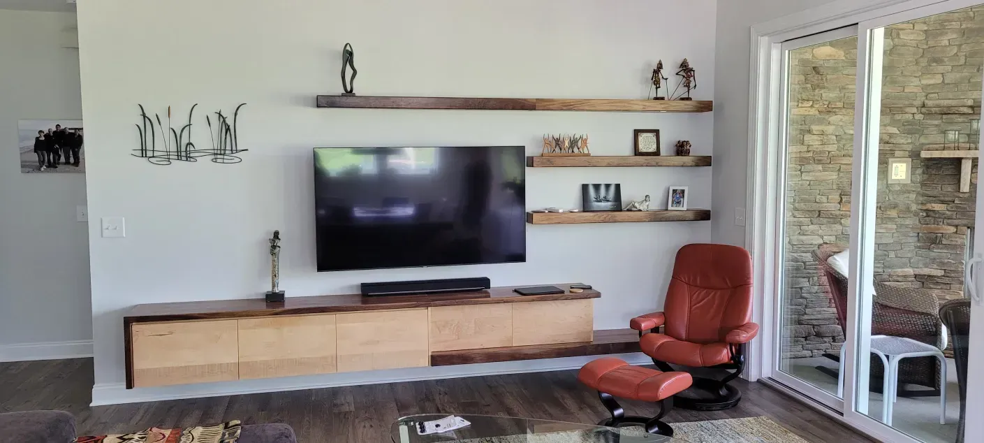 Modern living room with wall-mounted TV, floating shelves, and a red chair by a sliding glass door