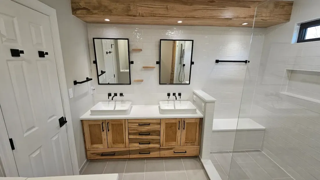 Modern bathroom with white tile, wood vanity, double mirrors, and glass shower enclosure