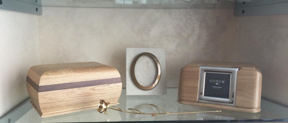 Scatola di legno, cornice e orologio digitale su una mensola di vetro. Gioielli di fronte.