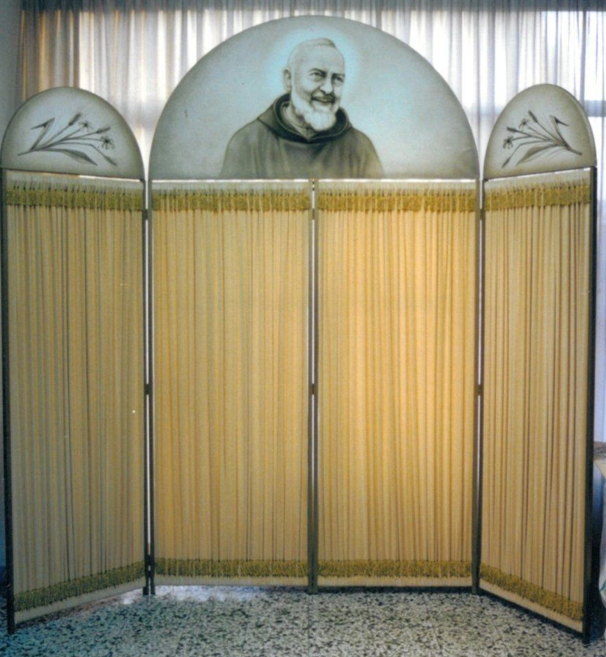 Separè con un'illustrazione di Padre Pio al centro. Tende color marrone chiaro.