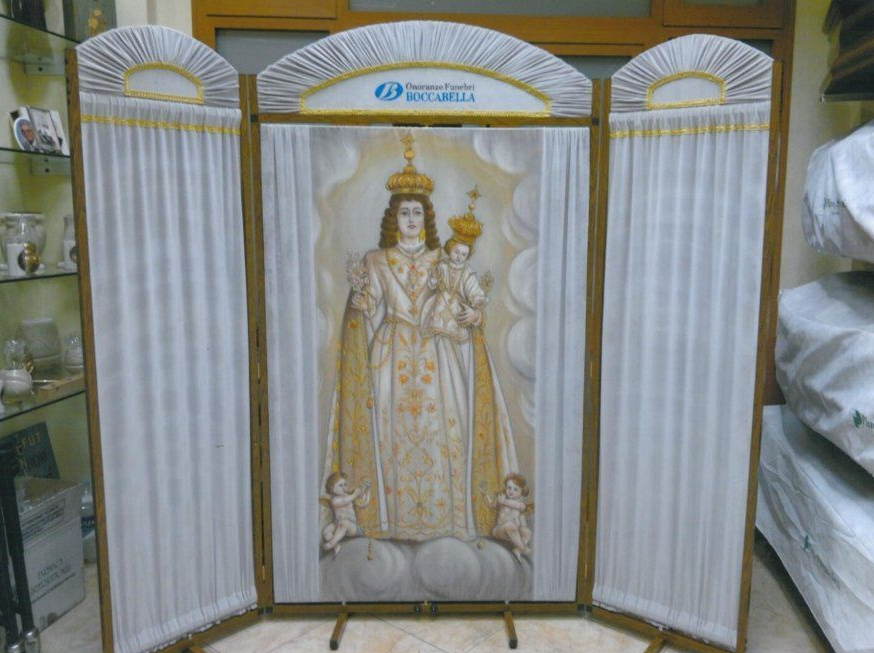 Trittico con dipinto centrale raffigurante la Madonna col Bambino incoronata, affiancata da tende bianche drappeggiate.