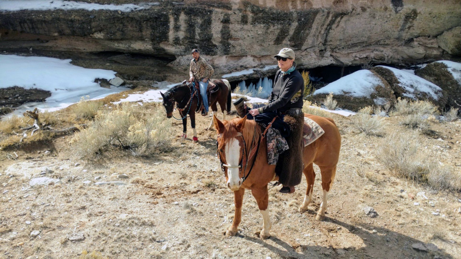 A group of people riding horses on a dirt road