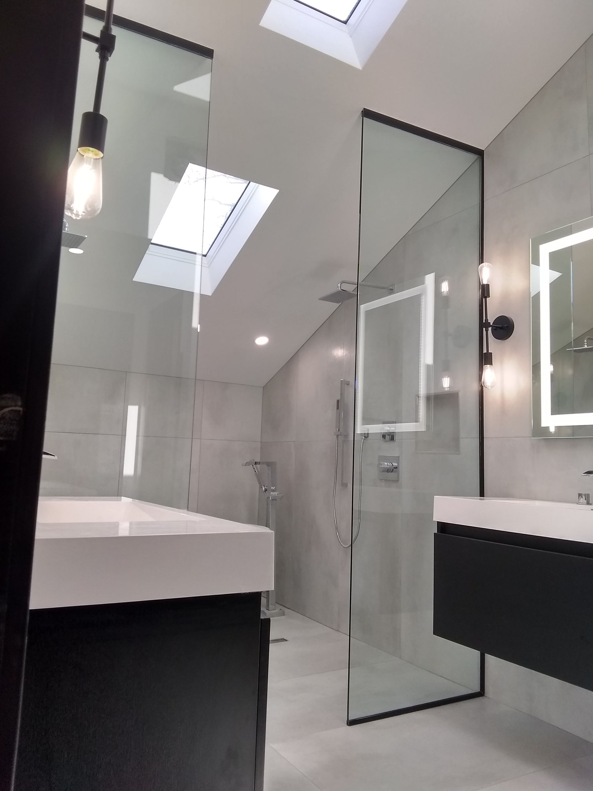 A bathroom with a walk-in shower, sink and mirror.