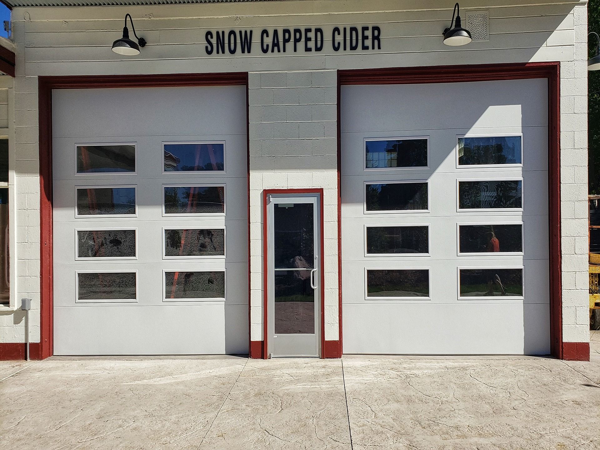 A white, single-story building with two large garage doors, a central glass door, and 