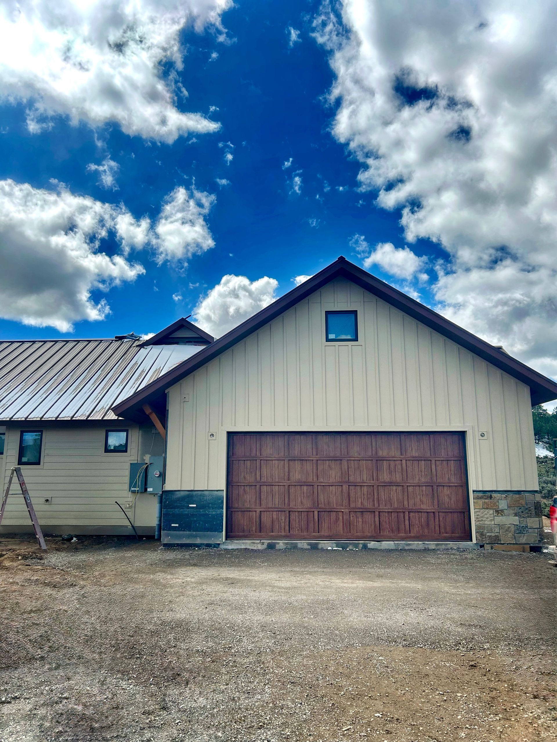 Beige garage with brown door under a blue sky with clouds