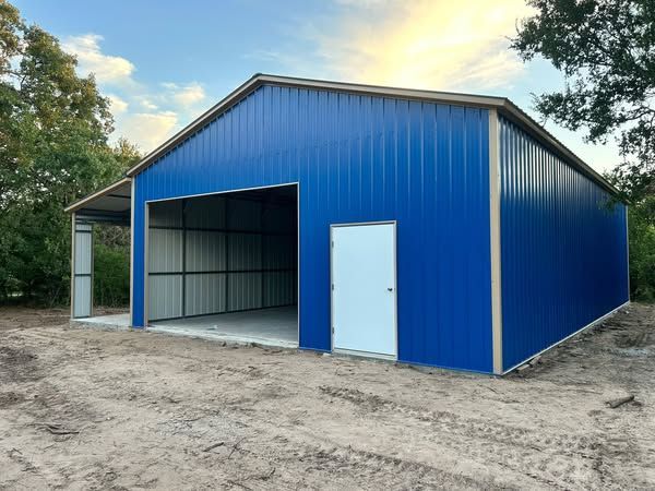 Blue metal storage barn with open bay door and white side door on a dirt lot