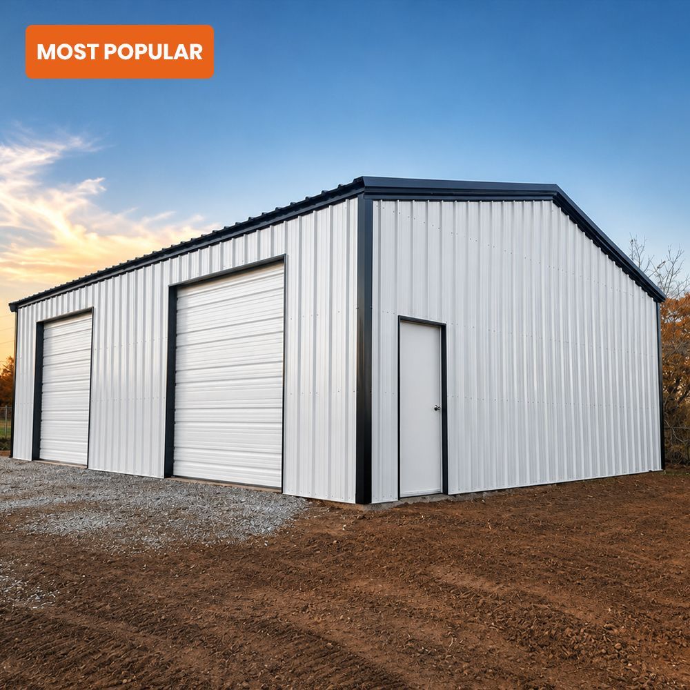 White metal storage building with two roll-up doors and a side entry door on a gravel lot at sunset