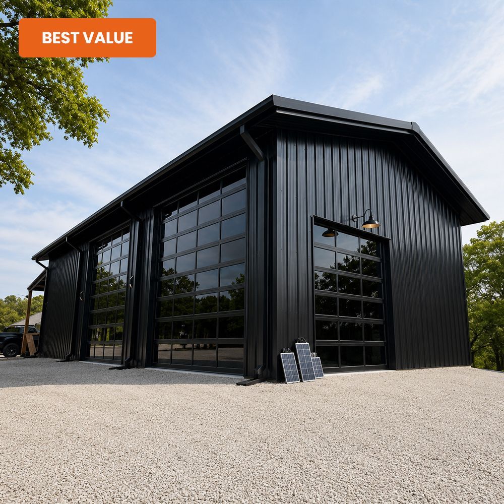 Black metal barn-style building with large glass doors on a gravel lot under a blue sky