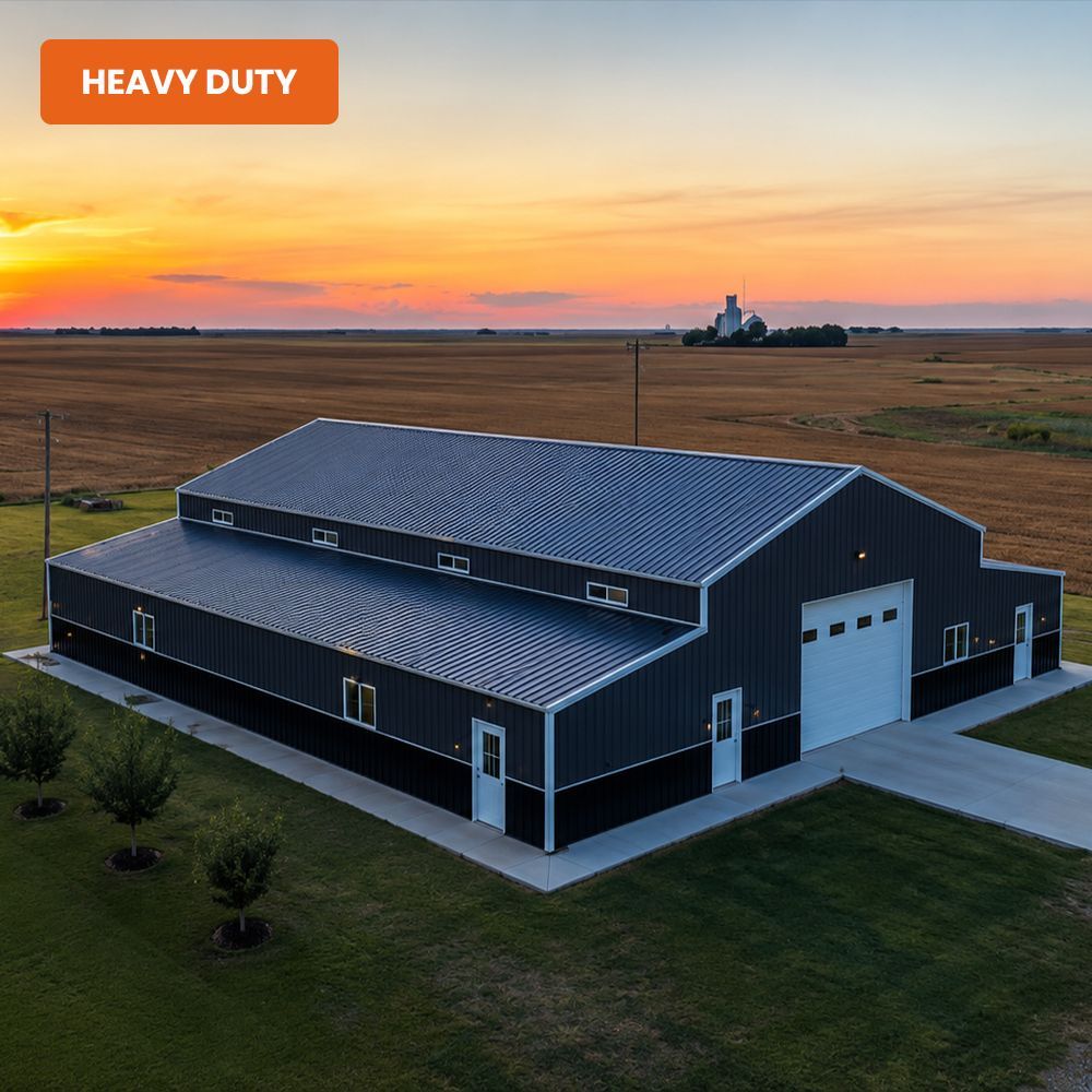 Heavy-duty dark metal warehouse at sunset in a rural field.
