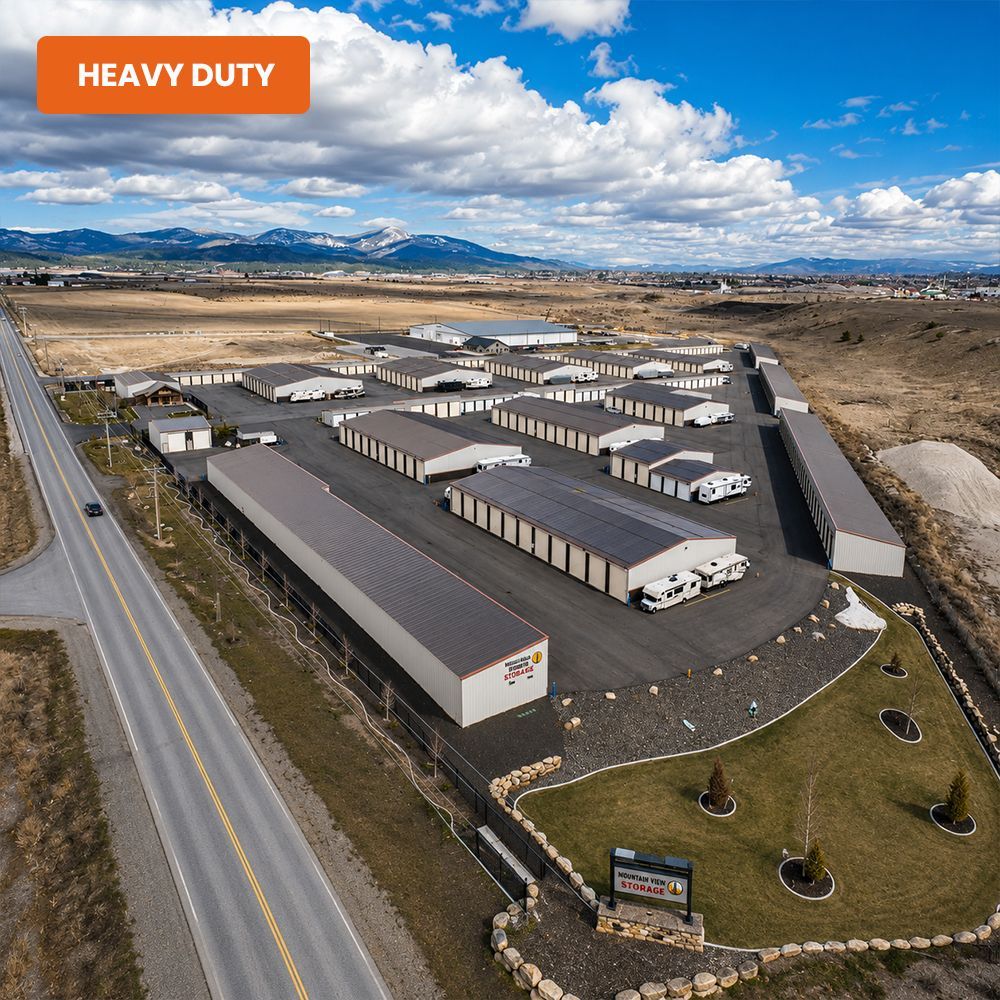Aerial view of a heavy-duty industrial warehouse complex beside a highway in a rural landscape.