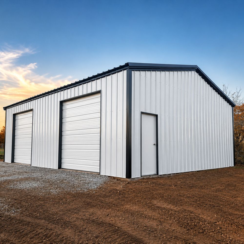 White metal storage building with three roll-up doors and a side entry on gravel at sunset