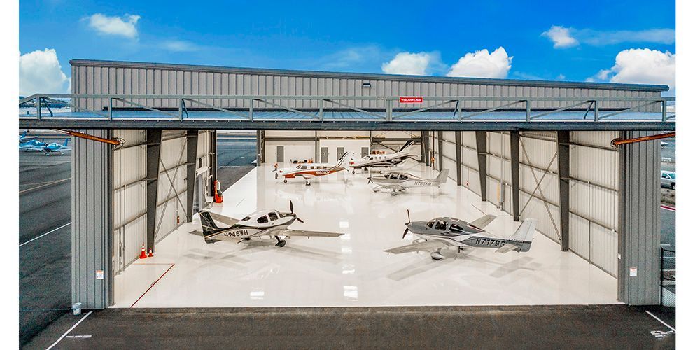 Small airport hangar with a jet aircraft inside under a blue sky