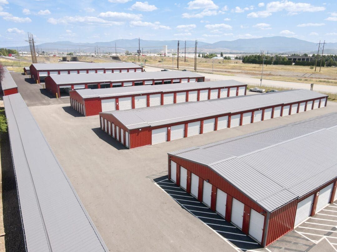 Aerial view of red-and-white storage warehouses in an industrial yard with mountains in the background