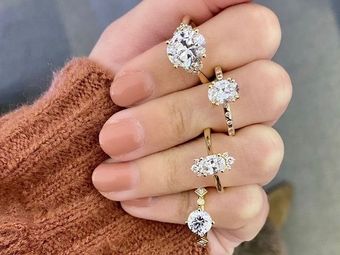 Hand wearing four diamond rings over a brown sweater sleeve