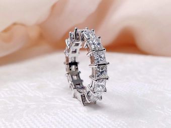 Silver gemstone eternity ring on a soft white fabric background