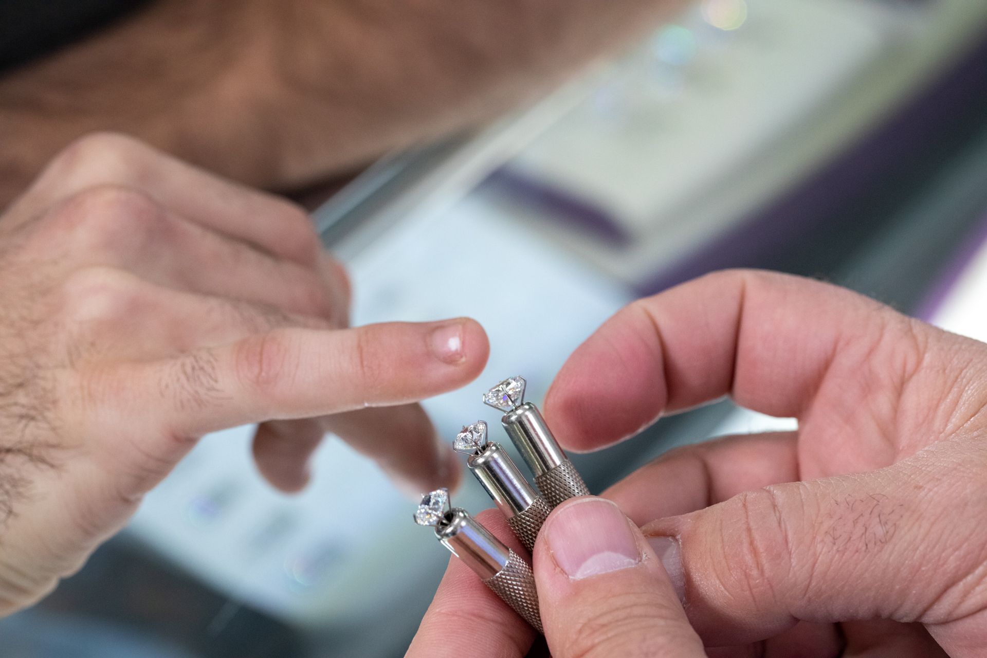 Hands holding a small metallic object while a finger points at it close up