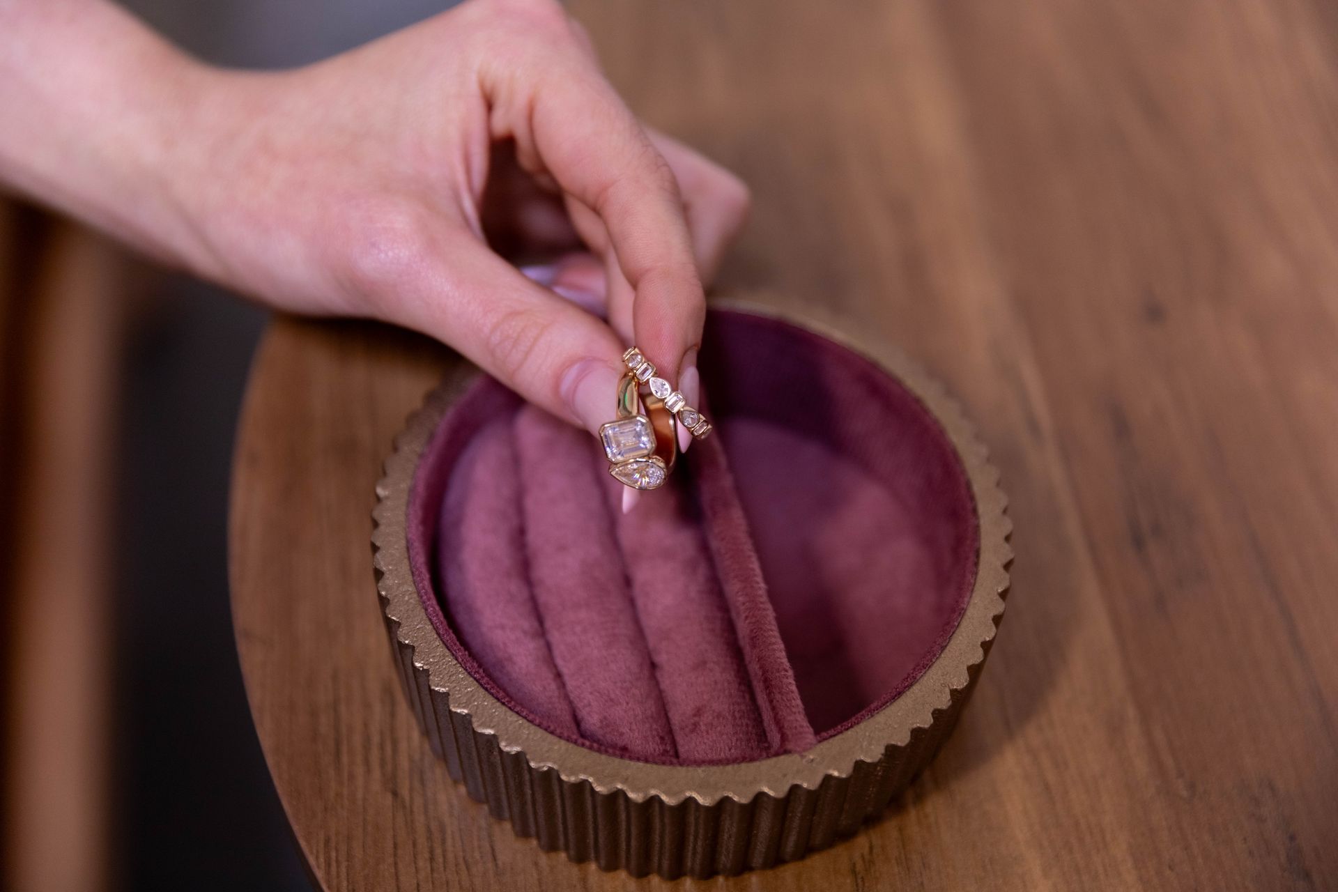 Hand placing a rose-gold ring into a purple velvet ring box