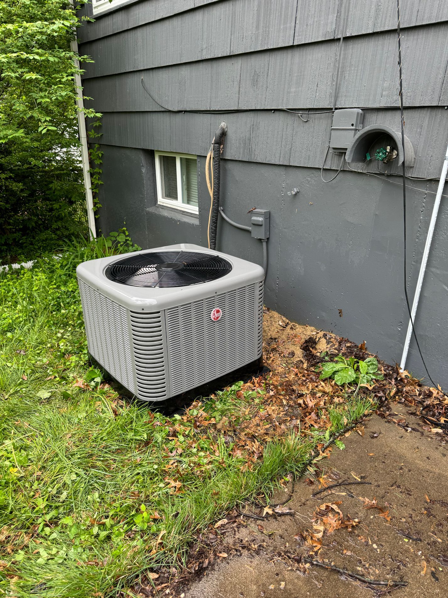 Technician servicing rooftop HVAC unit beside a red satellite dish under trees
