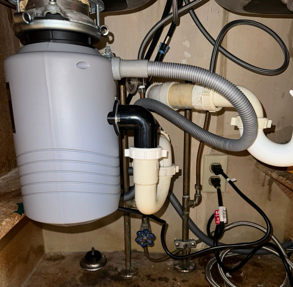 Chrome bathroom faucet and flexible hoses laid over plumbing blueprints