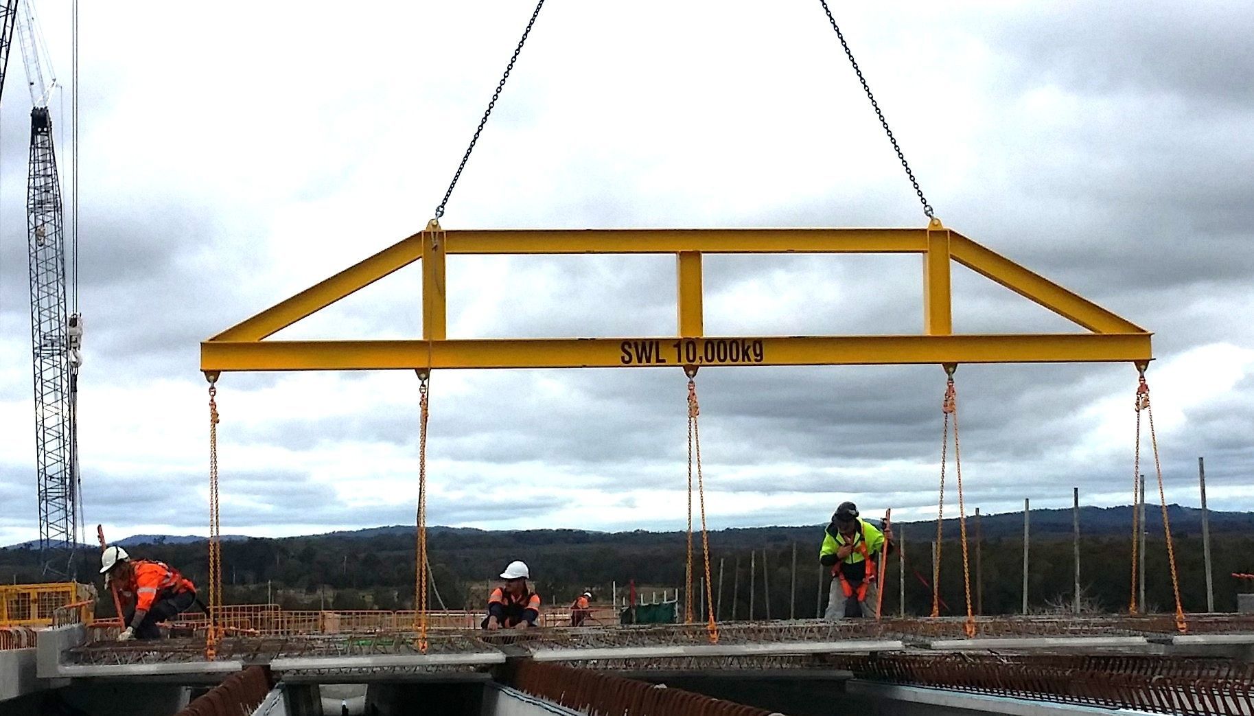 A yellow crane is lifting a beam that says ' a ' on it