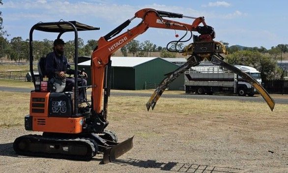 A man is driving a small excavator in a field.