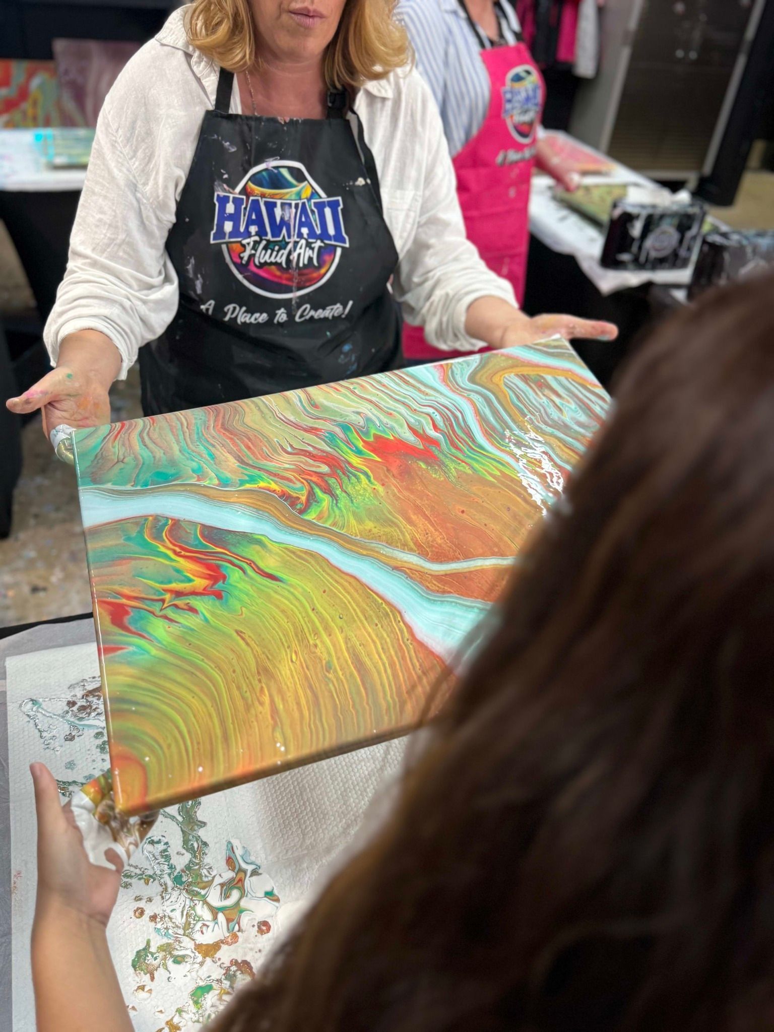 Woman holding a colorful marbled wood board at a craft table