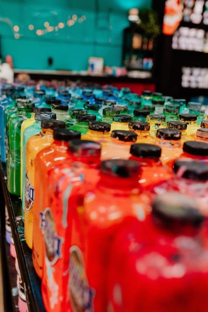 Rows of colorful bottled drinks with black caps on a store shelf