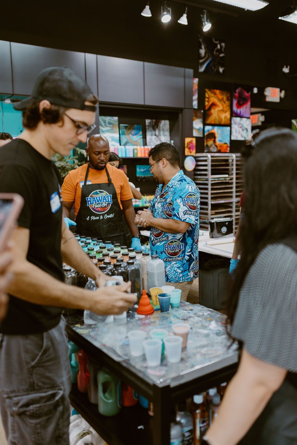 People gathered around a table with colorful drinks at an indoor event booth