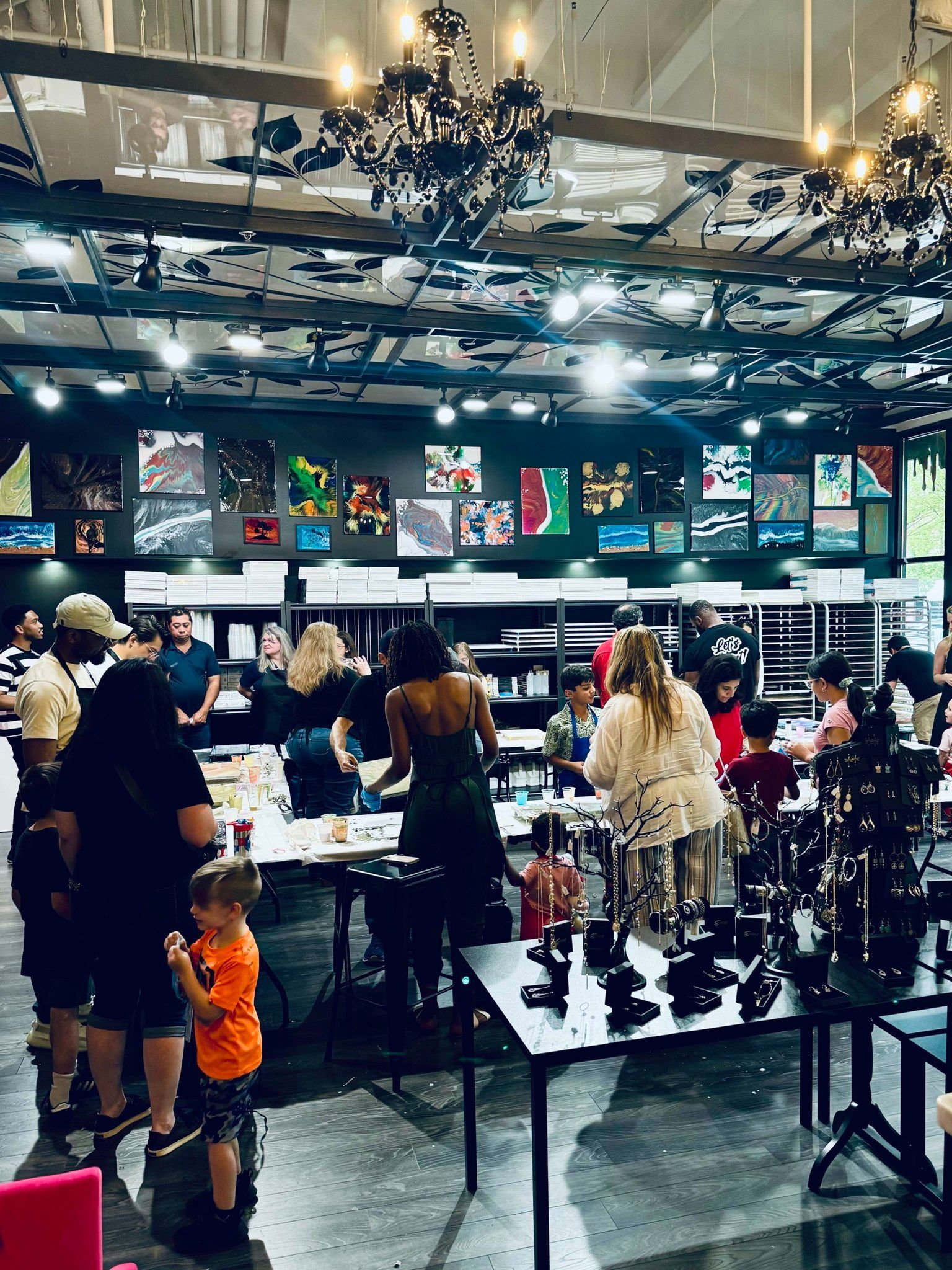 Crowded indoor market with people browsing stalls under chandeliers and colorful wall art