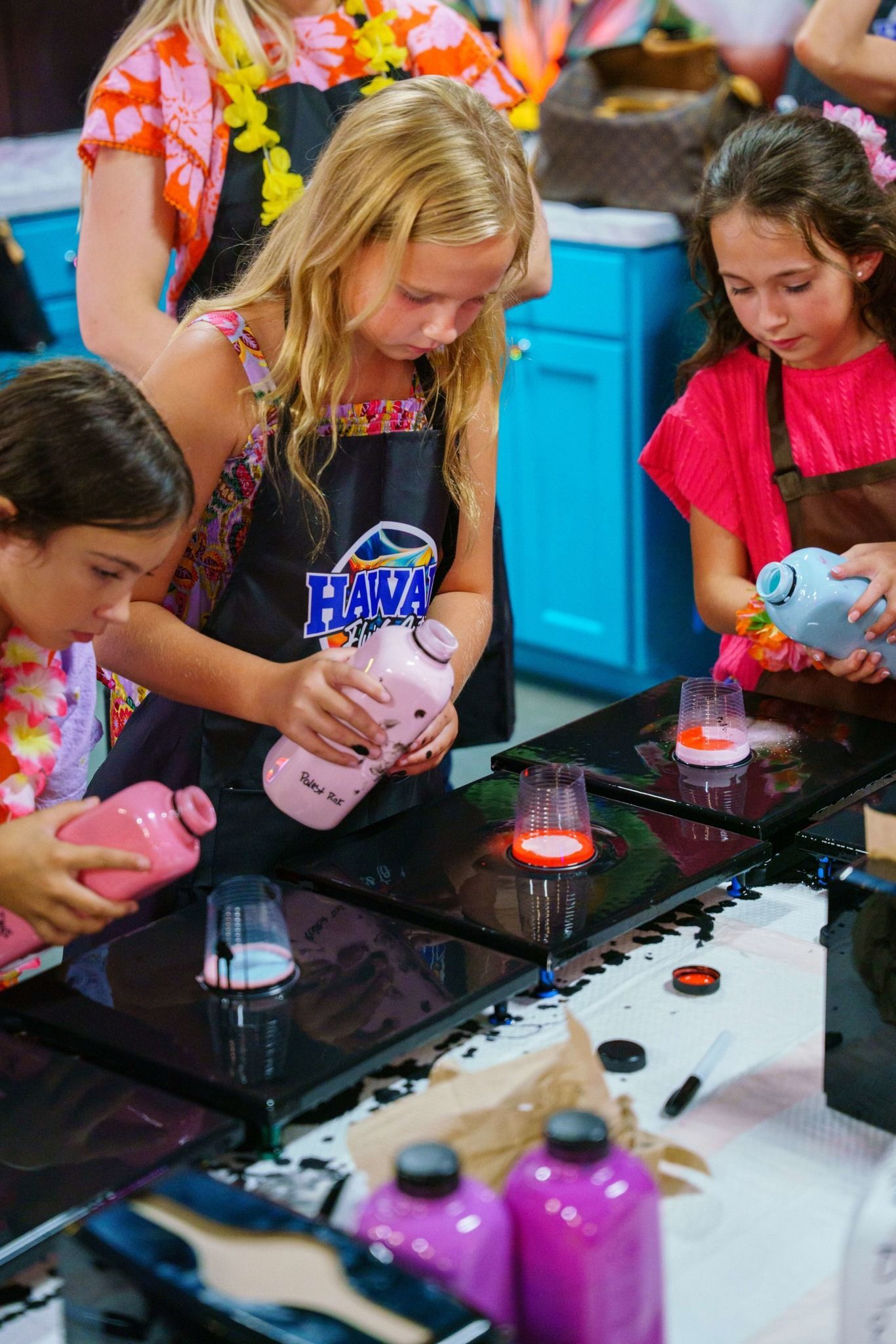Children making colorful drinks at a science activity table with glowing cups and bottles