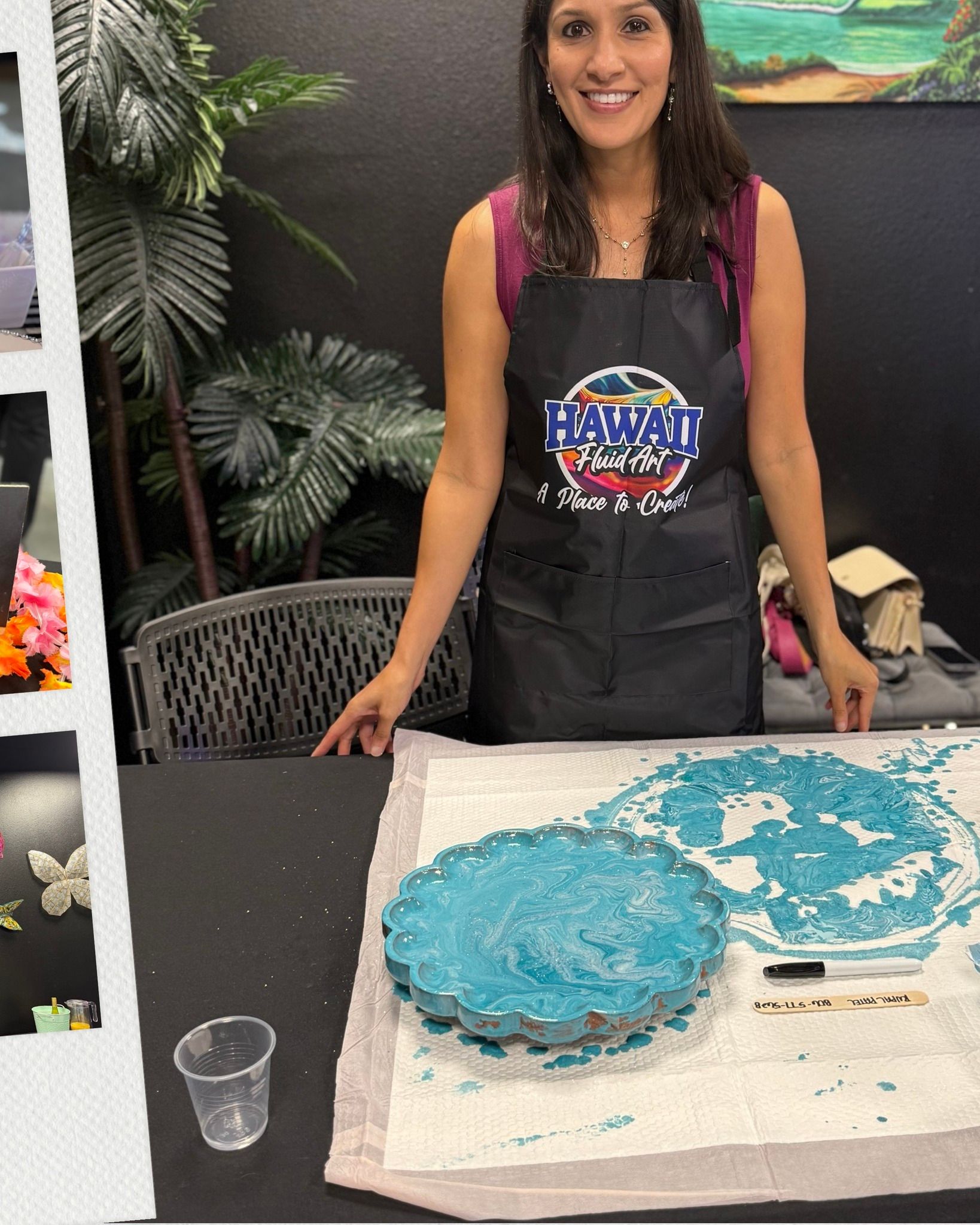 Woman in apron smiling beside a blue frosted cake on a table at a decorating workshop