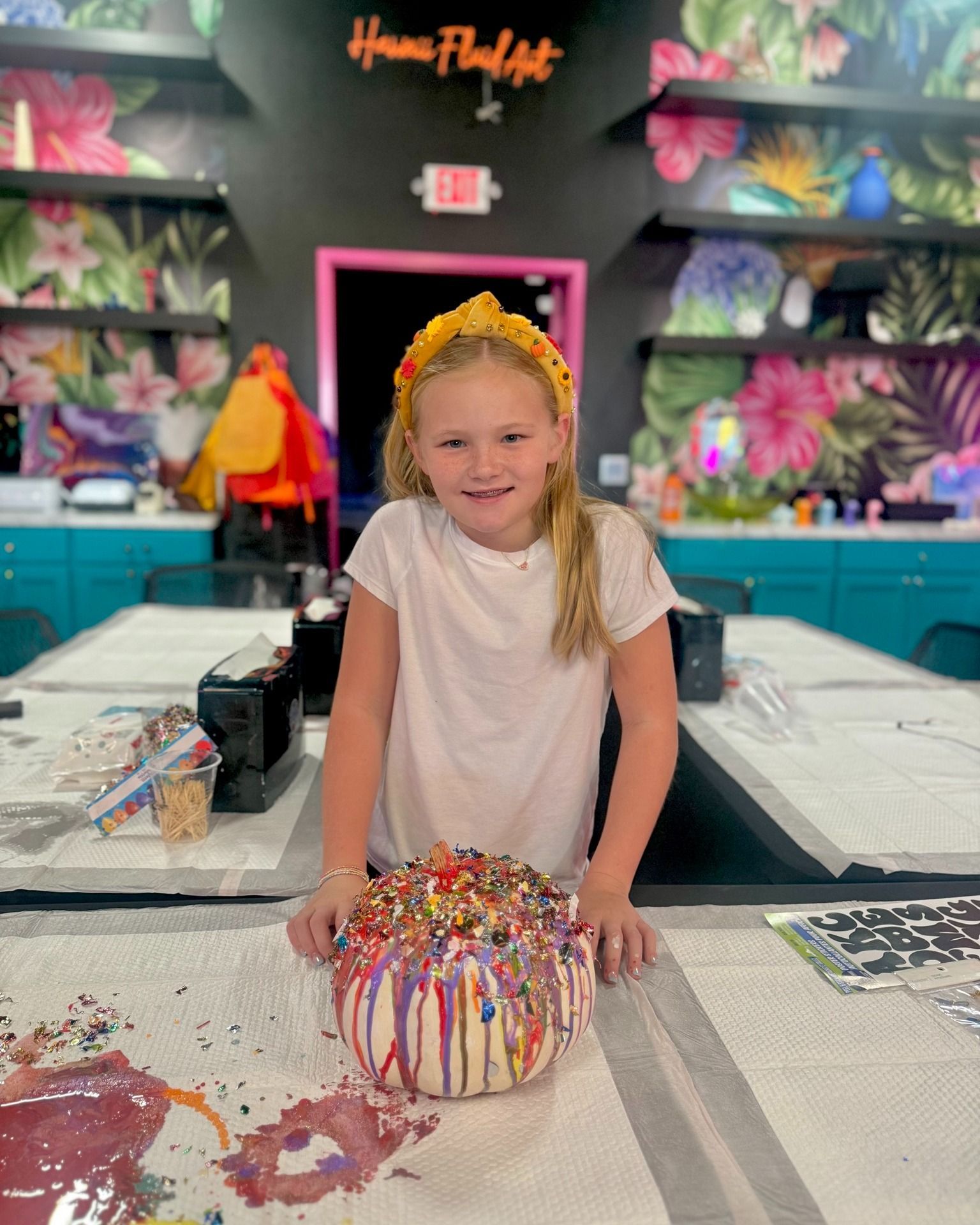 Girl smiling behind a colorful, sprinkle-covered cake in a bright party room