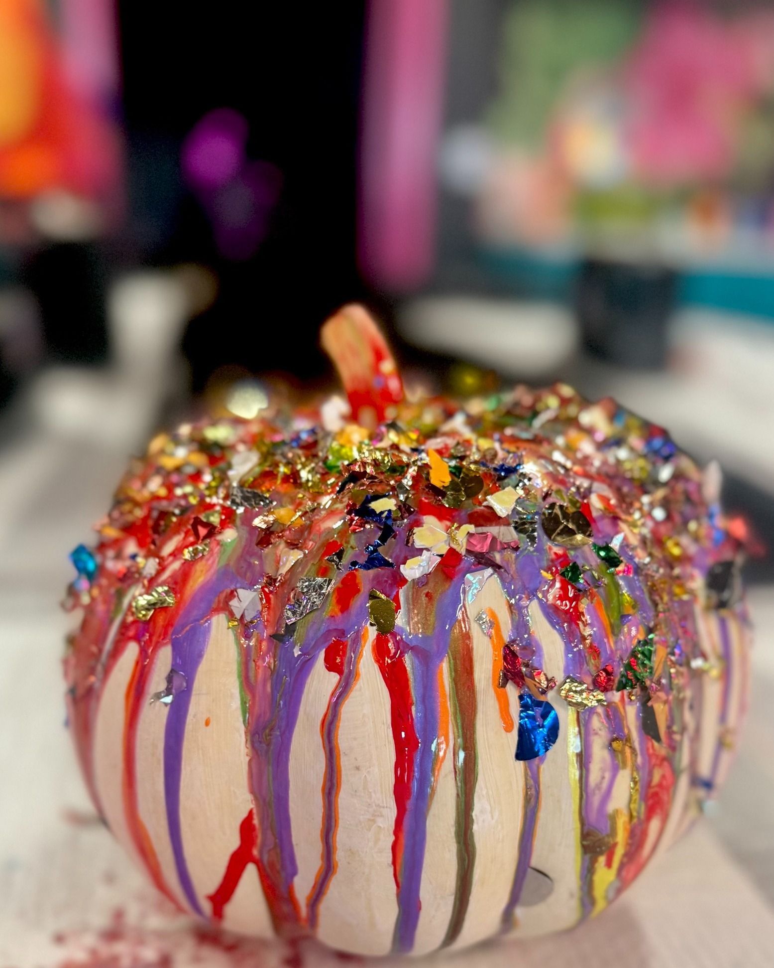Decorated pumpkin with colorful sprinkles and drizzled icing on a table