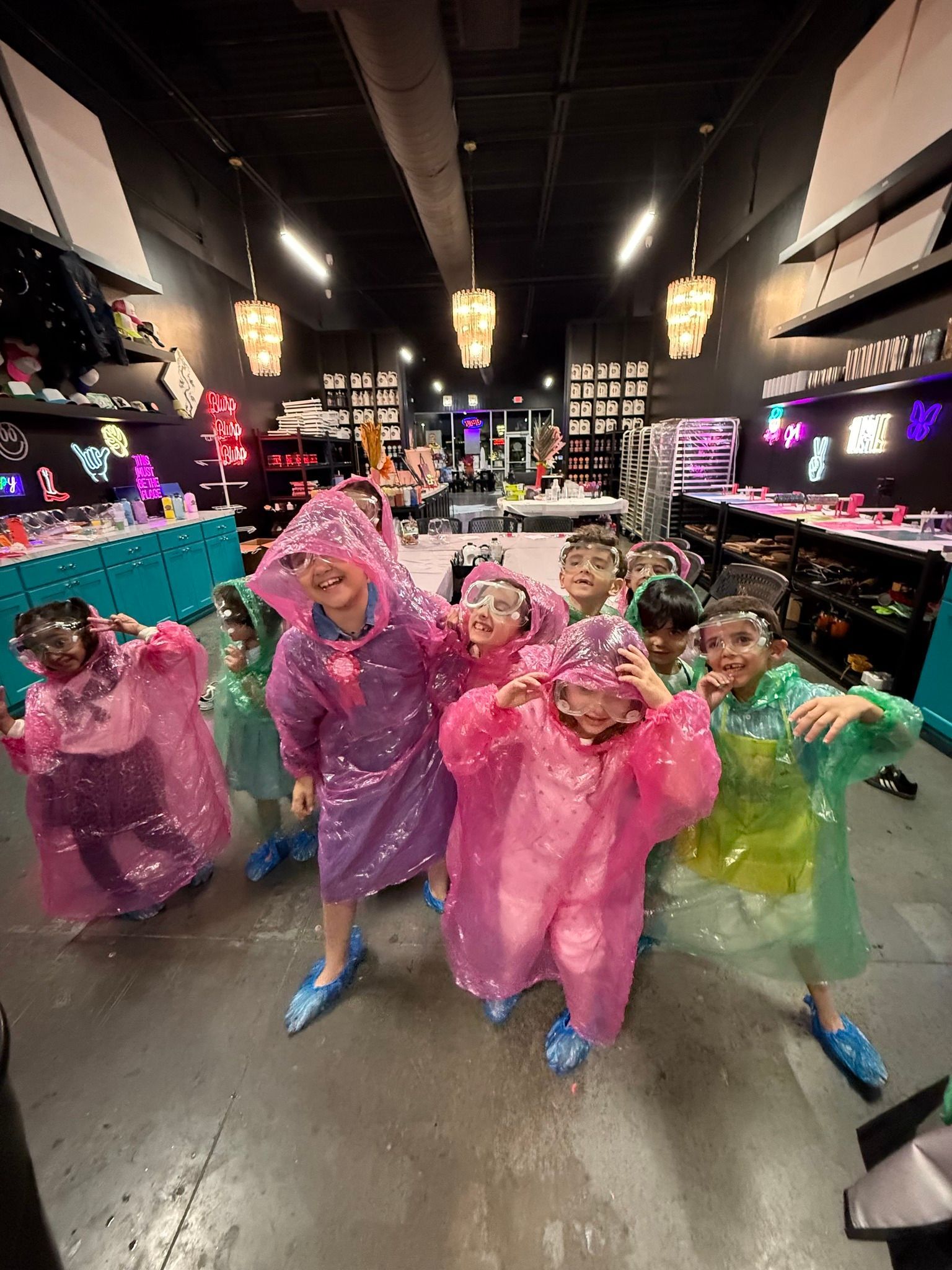 Five people in colorful ponchos pose and dance in a brightly lit store aisle.